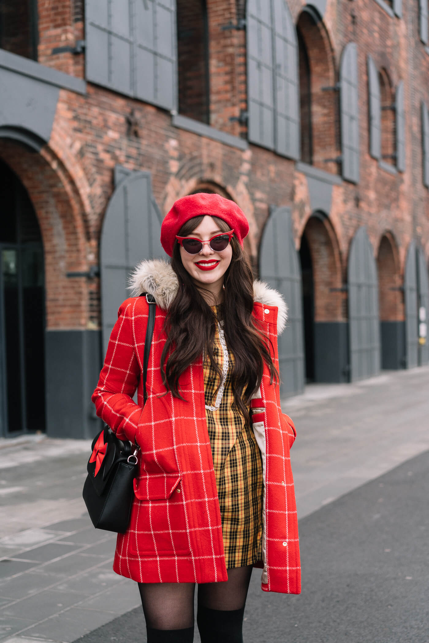 Evelyn Bourdon wearing a red checkered parka, vintage yellow plaid dress, red beret, minnie mouse bag, betty and veronica sunglasses, and black suede strappy block heels