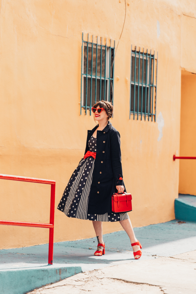 woman wearing modcloth pieces printed dress and black trench coat