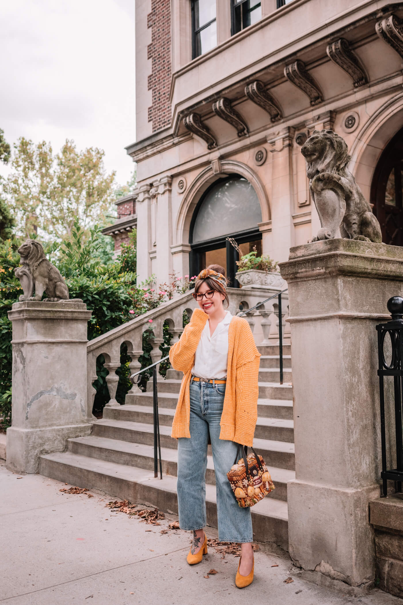 woman in denim jeans, white top, and yellow sweater