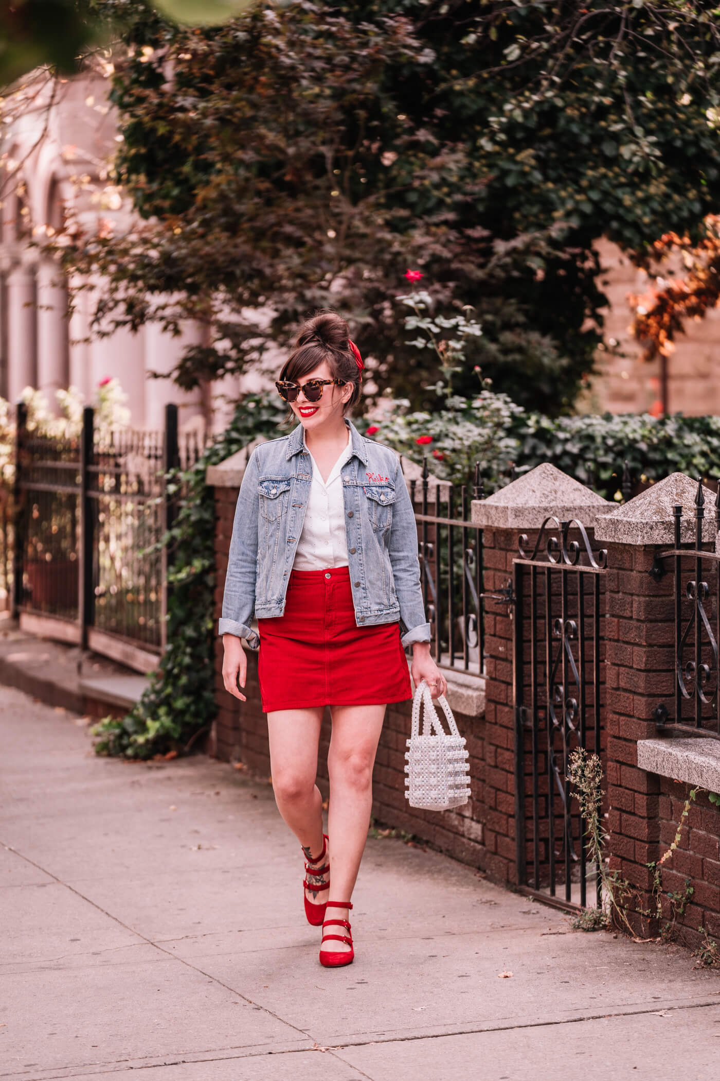 woman in white top, red skirt, and denim jacket