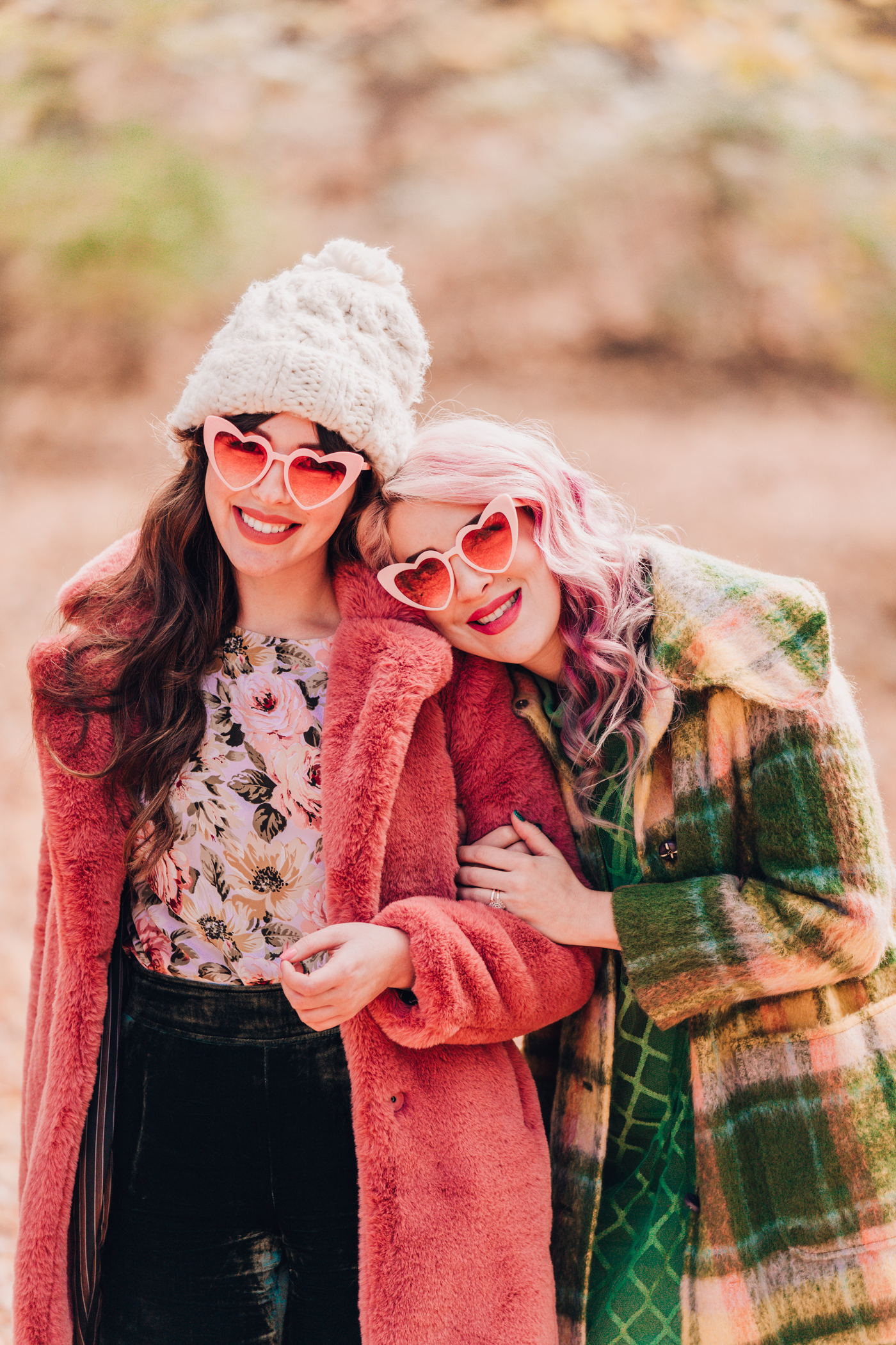 woman wearing green and Pink faux fur coat and pink heart shaped sunglasses