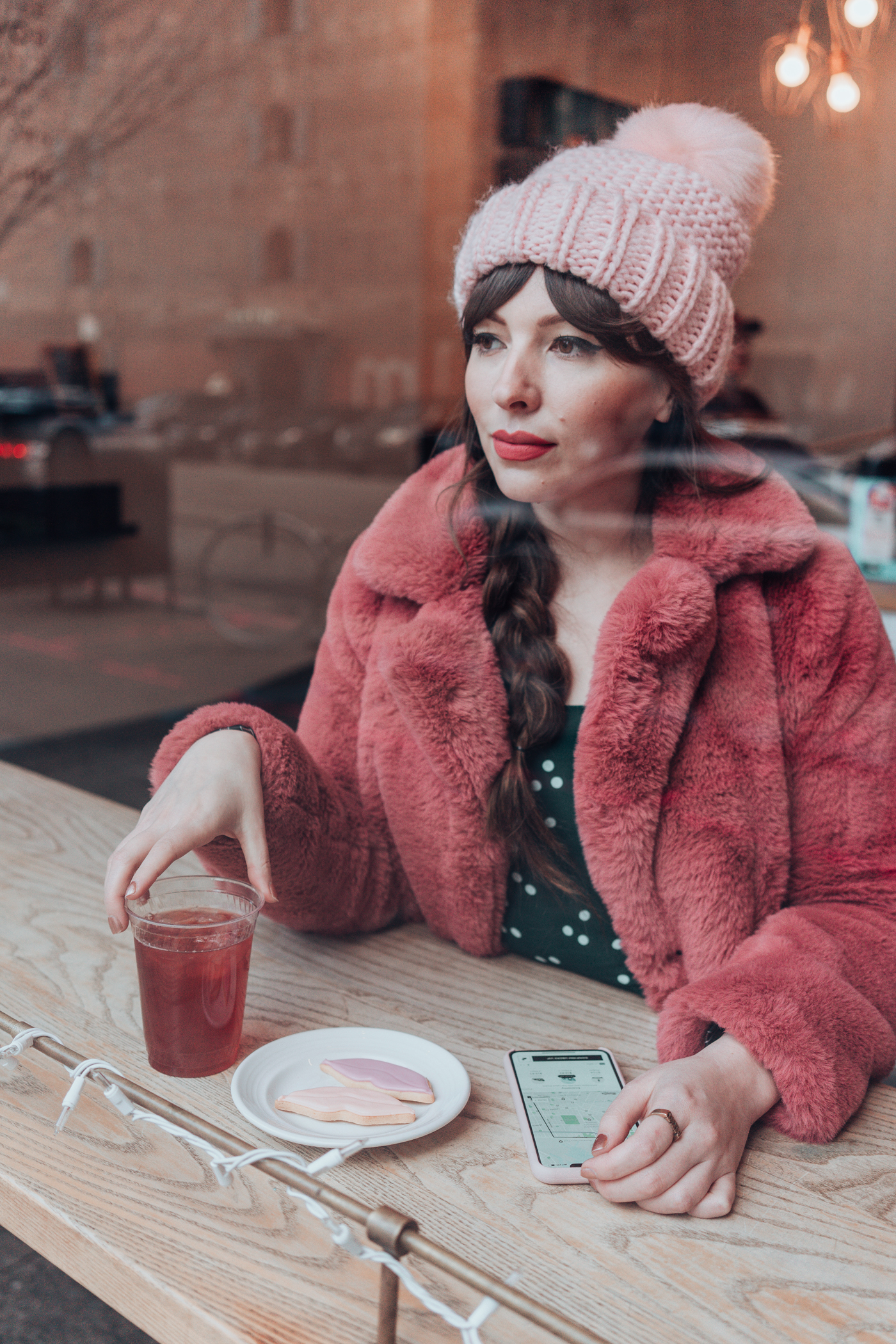 woman showing Uber rewards app on phone, drinking coffee, and eating cookies 