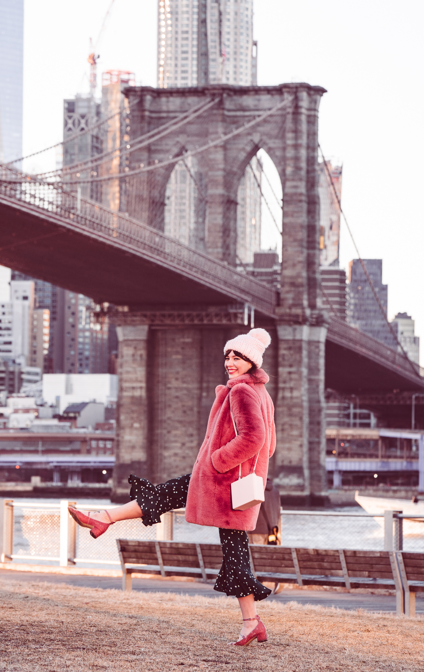 woman smiling in green printed dress and pink coat 