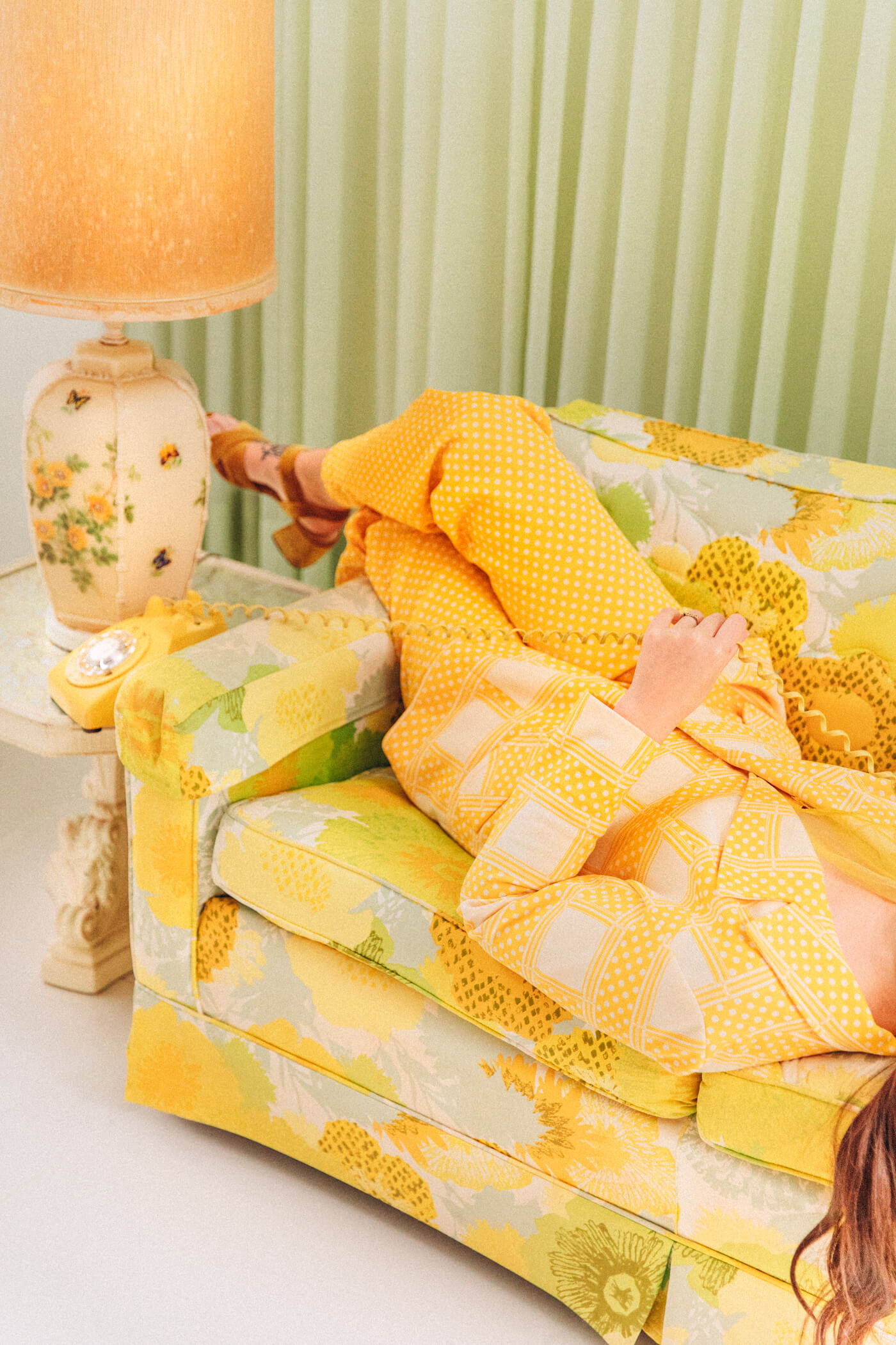 woman using a vintage telephone and laying down in a vintage sofa for Past lives of future heirlooms