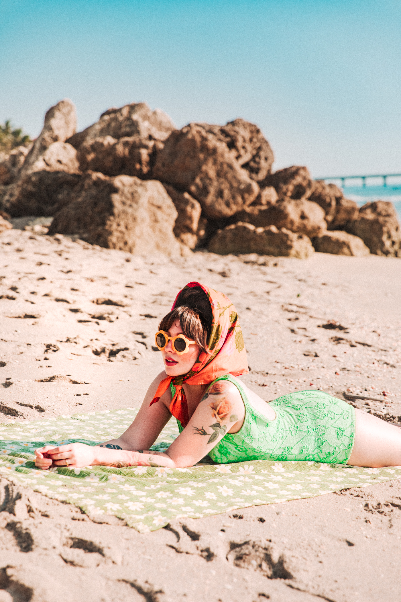 woman wearing a one piece bathing suit and laying down at the shore