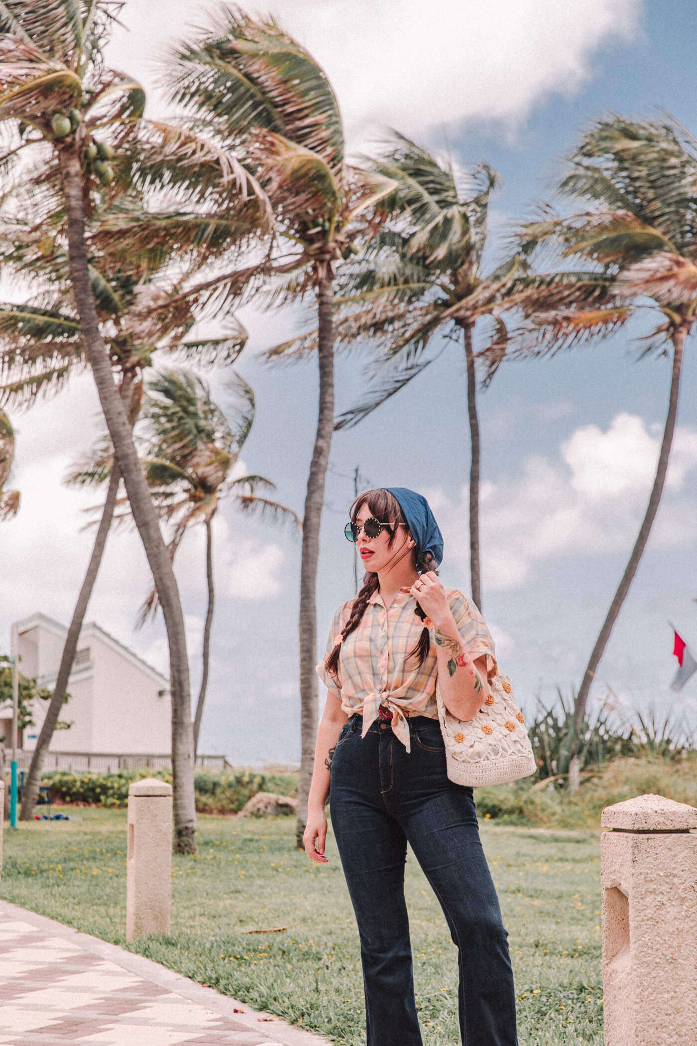 woman wearing bell bottom jeans and shirt with coconut tress on the background