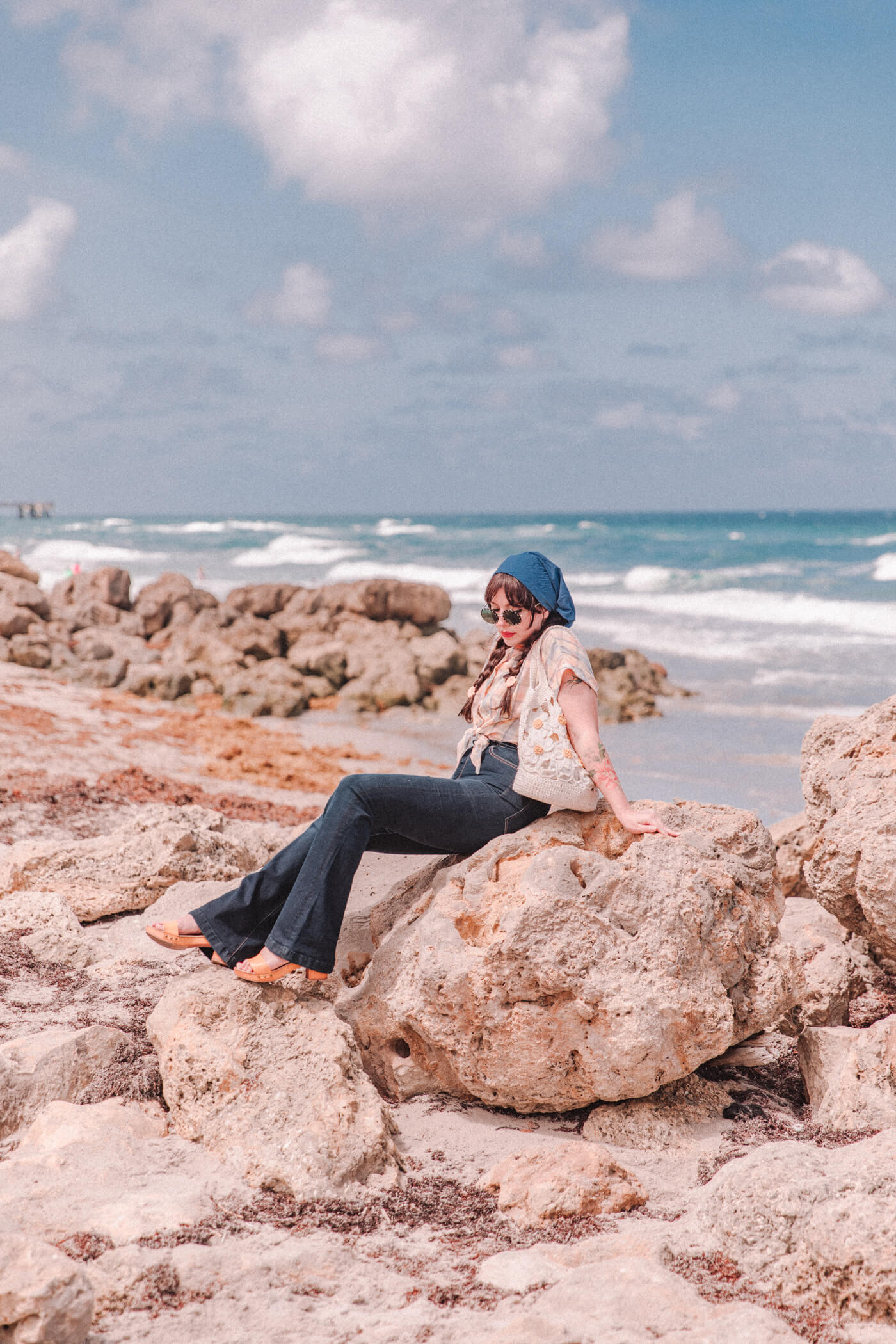 woman wearing at the beach wearing bell bottom jeans and shirt 