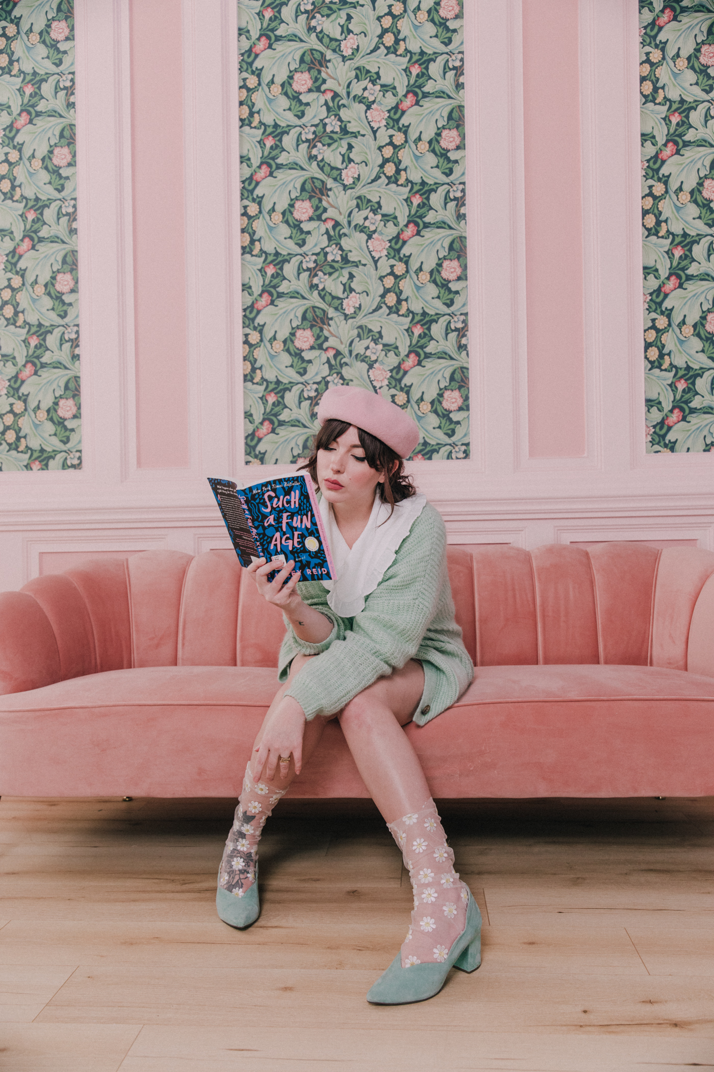 woman sharing sitting a t pink couch and talking about books 