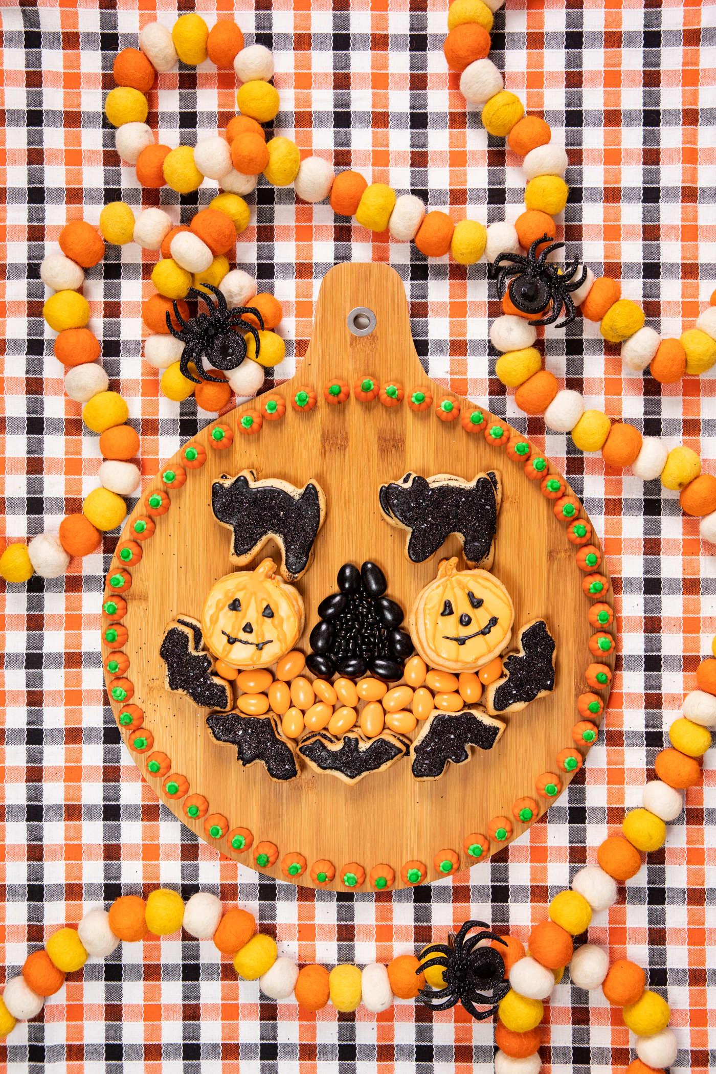 wooden halloween snack board with assorted orange and black snacks assembled to resemble a pumpkin