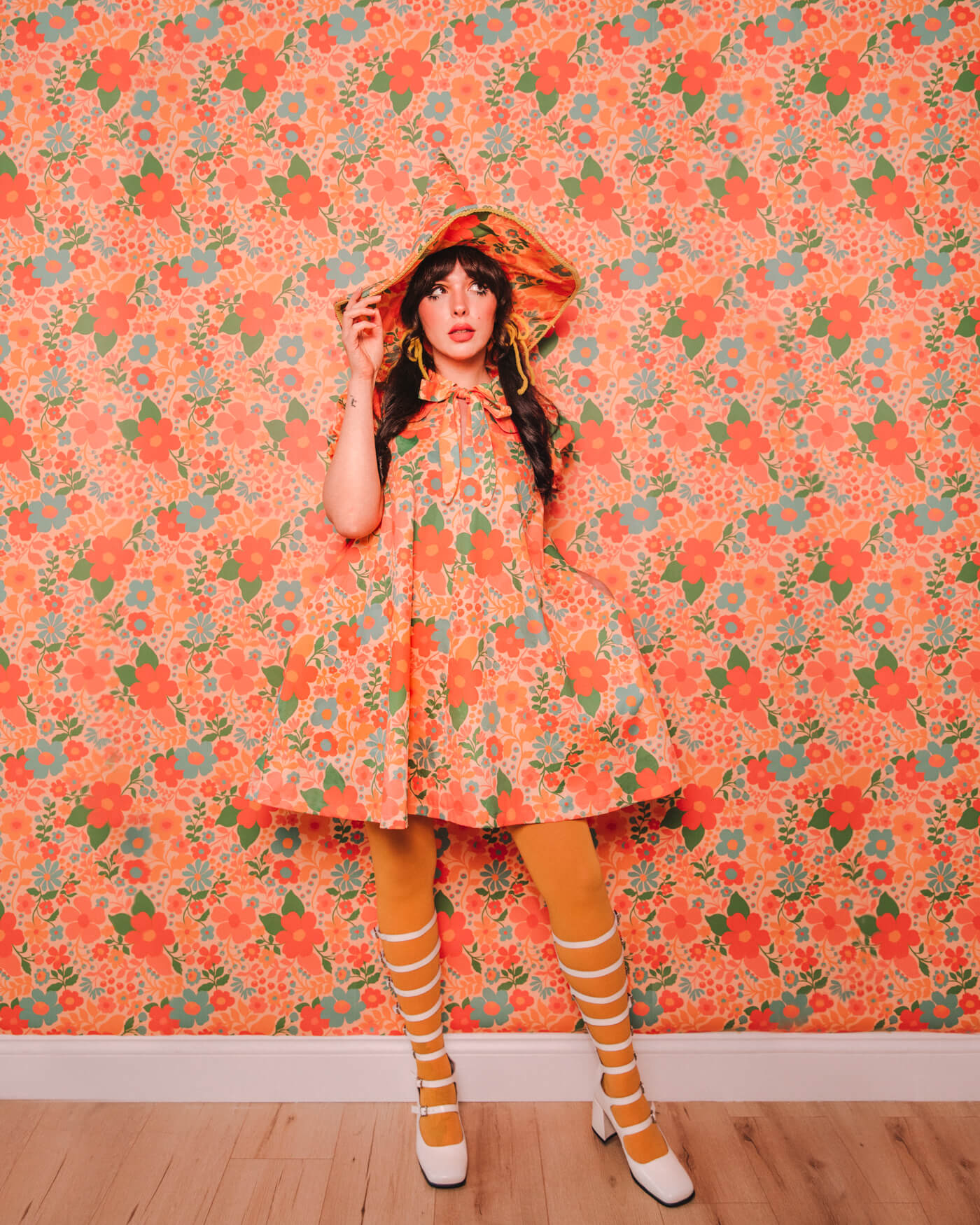 Evelyn Bourdon wearing a handmade dress and matching witch hat made out of Spoonflower fabric, in front of matching wallpaper in the same print.