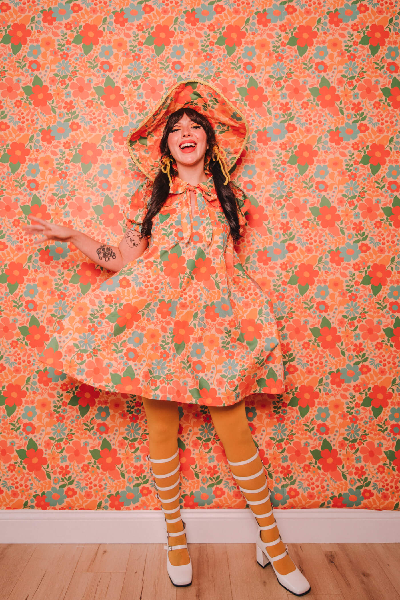 Evelyn Bourdon wearing a handmade dress and matching witch hat made out of Spoonflower fabric, in front of matching wallpaper in the same print.