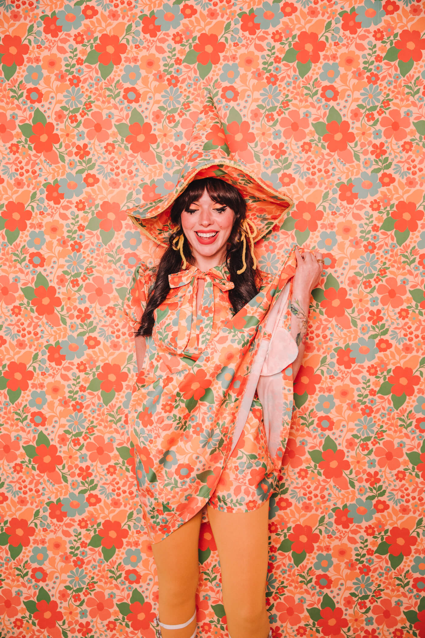 Evelyn Bourdon wearing a handmade dress and matching witch hat made out of Spoonflower fabric, in front of matching wallpaper in the same print.