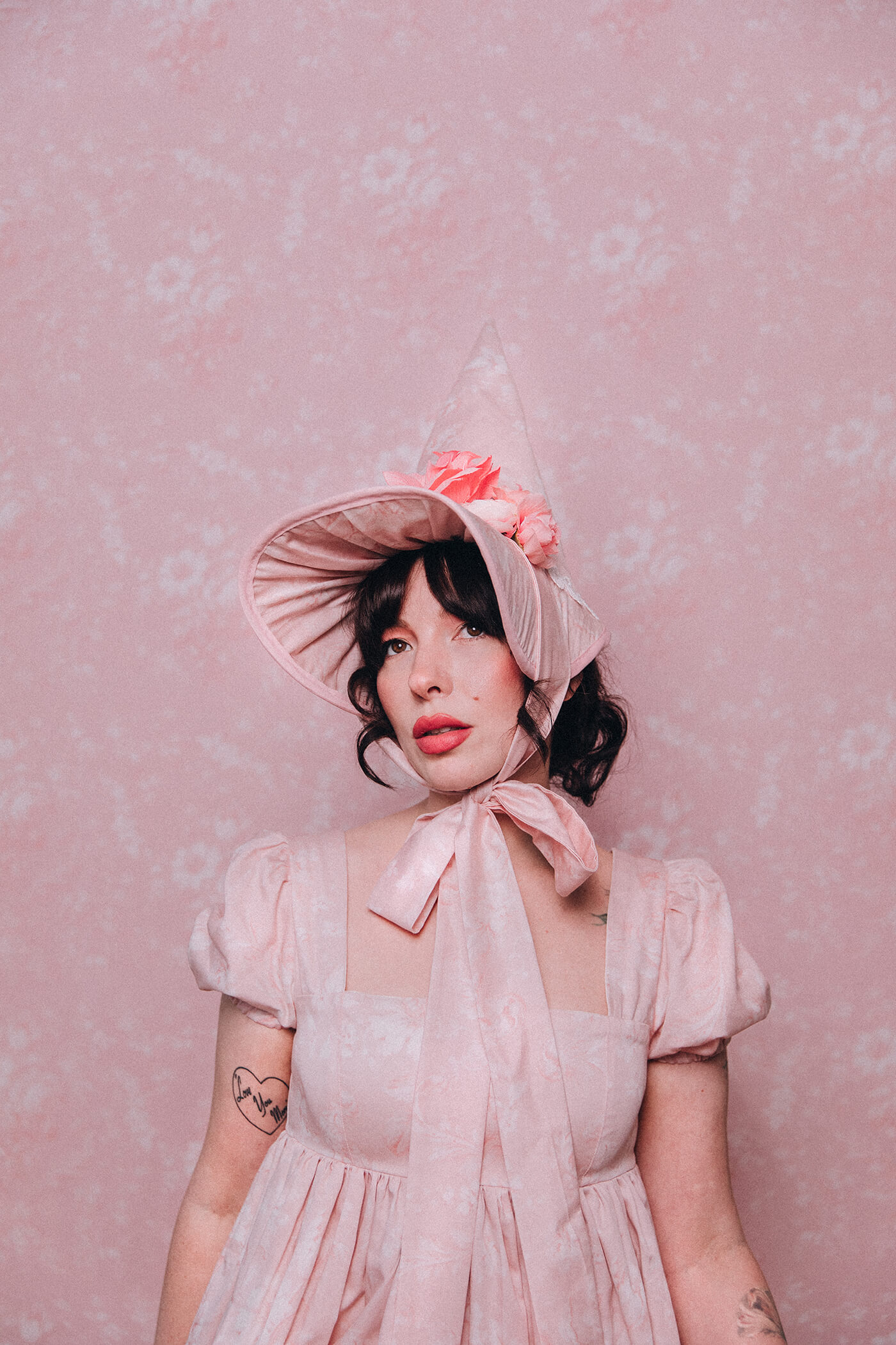 Evelyn Bourdon wearing a handmade dress and matching witch hat made out of Spoonflower fabric, in front of matching wallpaper in the same print.