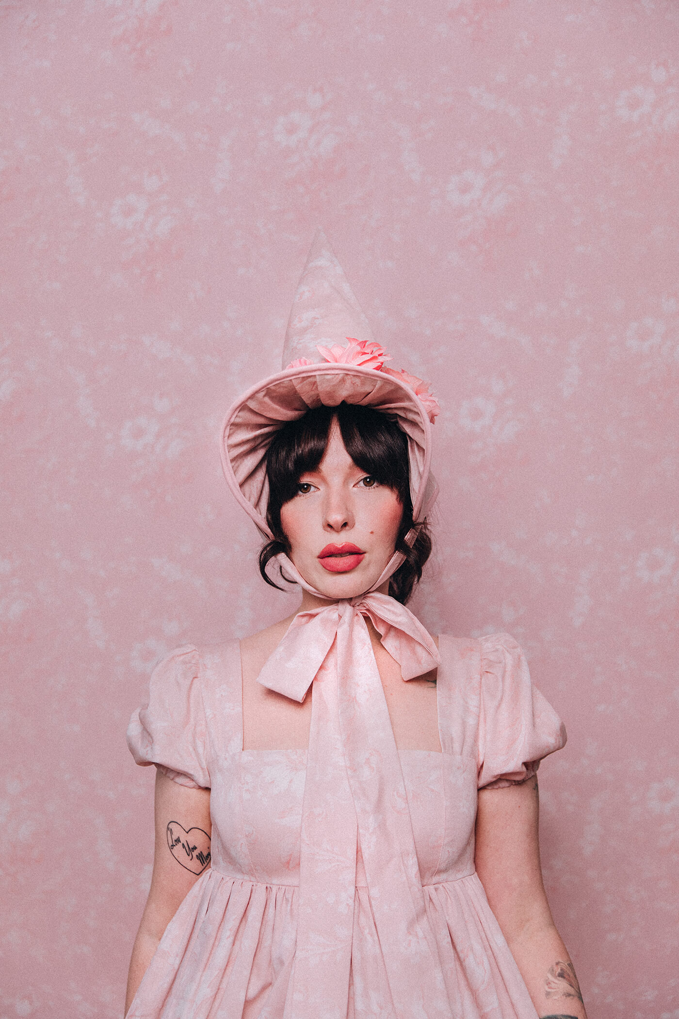 Evelyn Bourdon wearing a handmade dress and matching witch hat made out of Spoonflower fabric, in front of matching wallpaper in the same print.