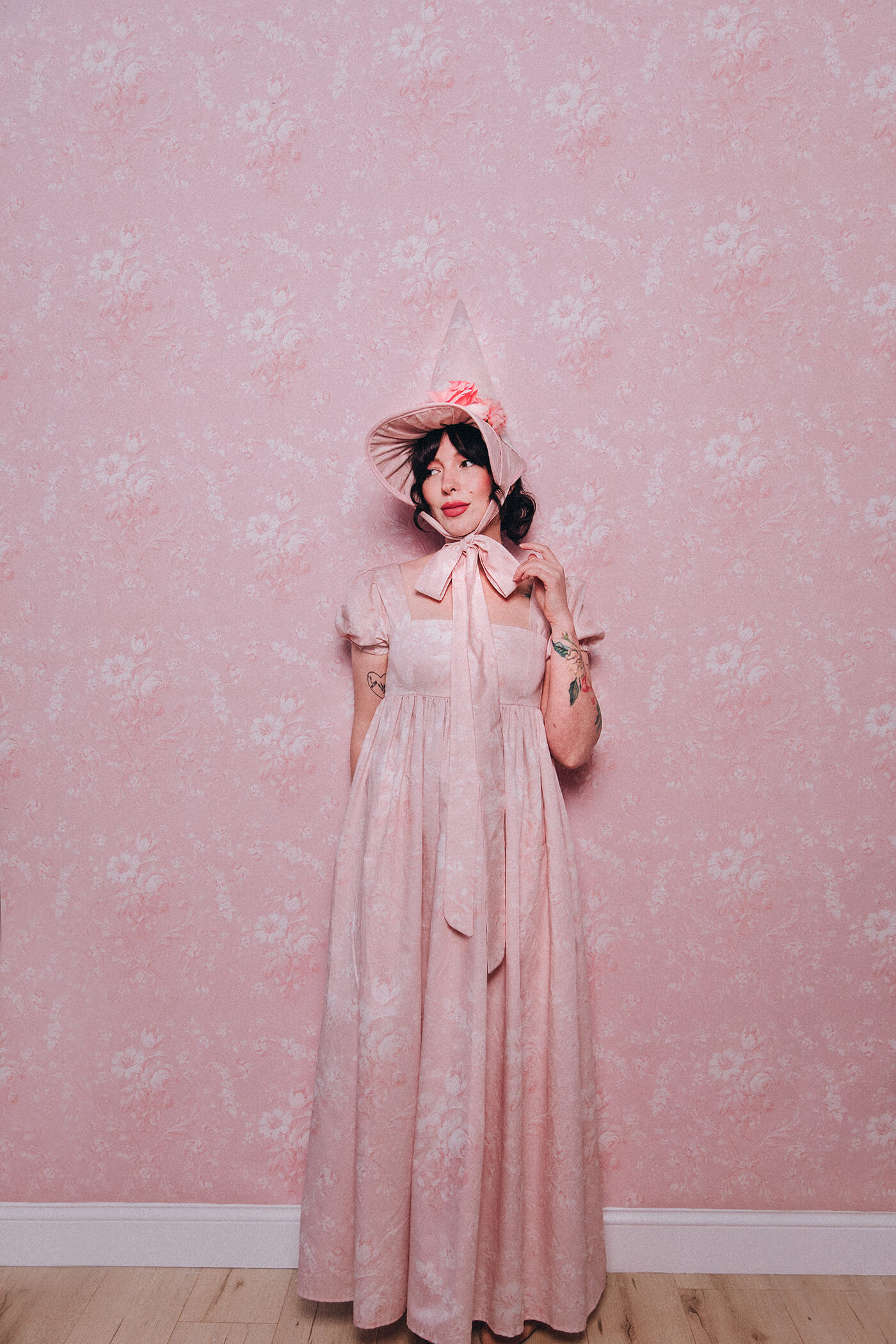 Evelyn Bourdon wearing a handmade dress and matching witch hat made out of Spoonflower fabric, in front of matching wallpaper in the same print.