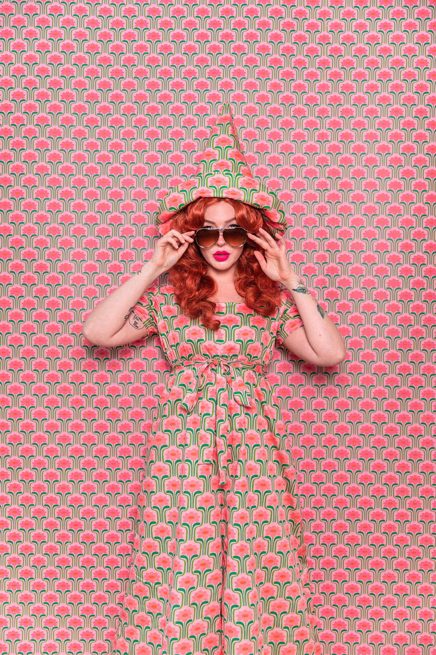 Evelyn Bourdon wearing a handmade dress and matching witch hat made out of Spoonflower fabric, in front of matching wallpaper in the same print.