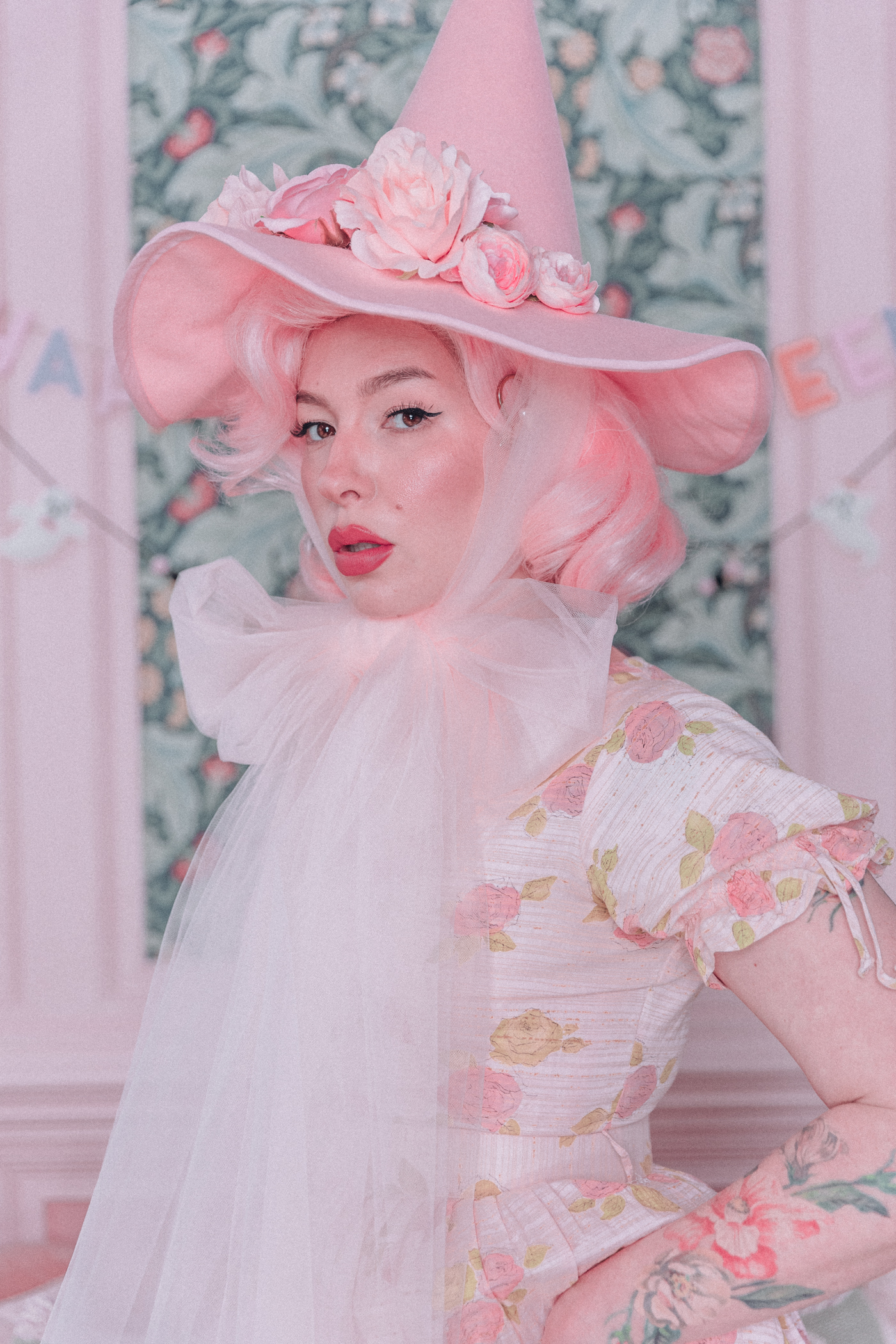 Woman wearing a pink witch hat with flowers and tulle ties